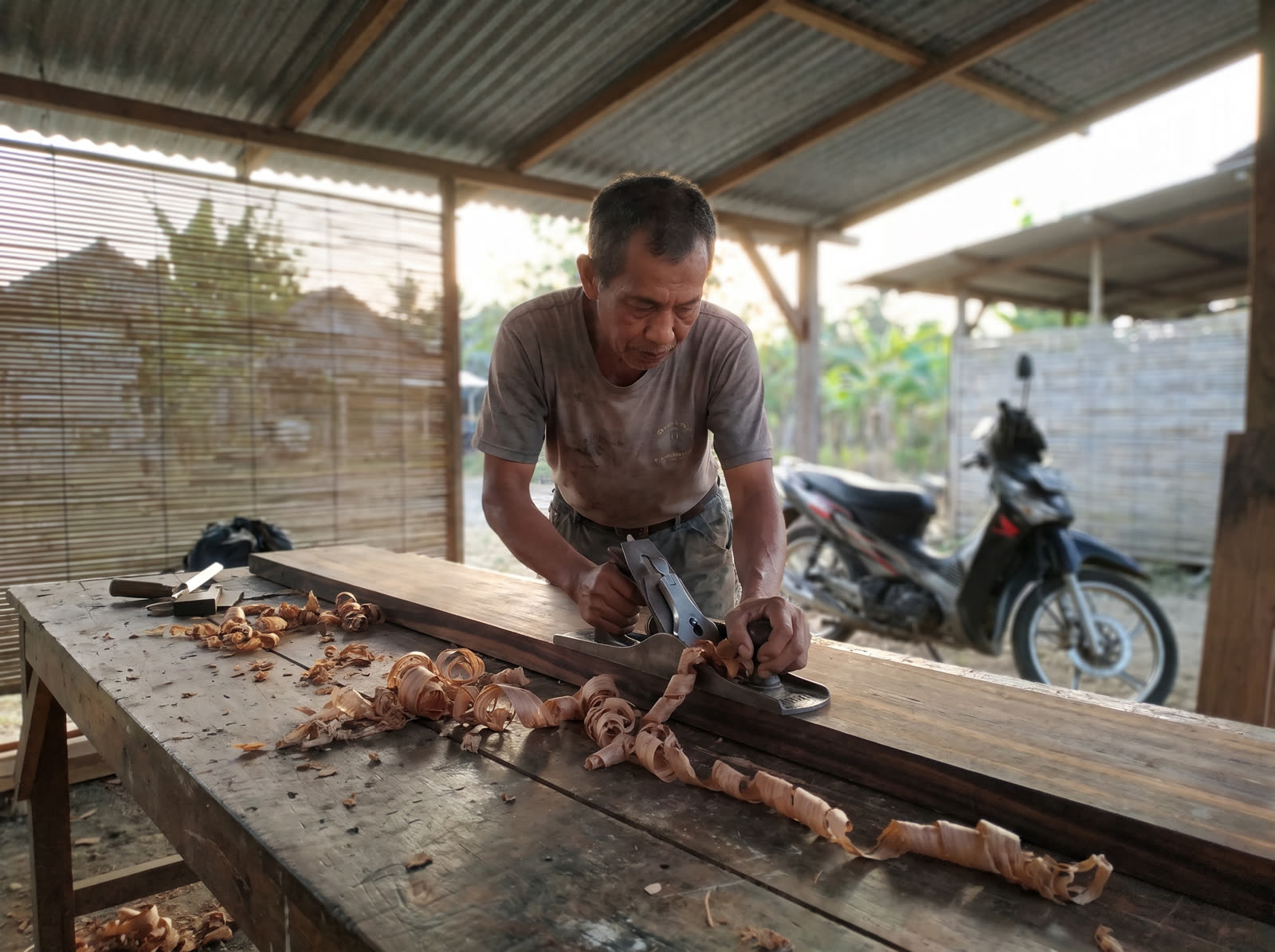 Carpenter hand-planing a cedar stave in an island workshop